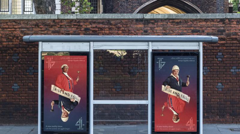 Two posters on a bus stop with text that reads ‘Rise and Fall, A new reality show, let the power struggle begin’. There’s an image of a judge in red clothing holding a gavel, mirroring an image of a man wearing a hard-hat, overalls and holding a hammer.