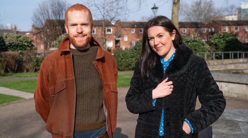 Light-haired man with beard and brown haired woman stood in street