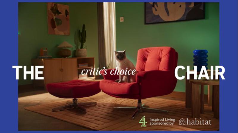 A cat sat on a red armchair in a decorated living room, alongside the text 'The Critic's Choice Chair' with Inspired Living Sponsored By Habitat in the corner.