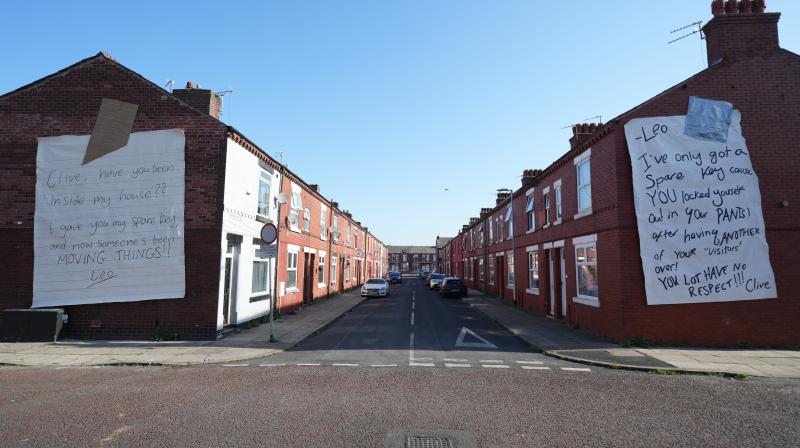 It shows two houses in Manchester that have two very large notes on the side of the buildings. The text shows a neighbourly dispute signed off by the characters from the upcoming drama Tip Toe.
