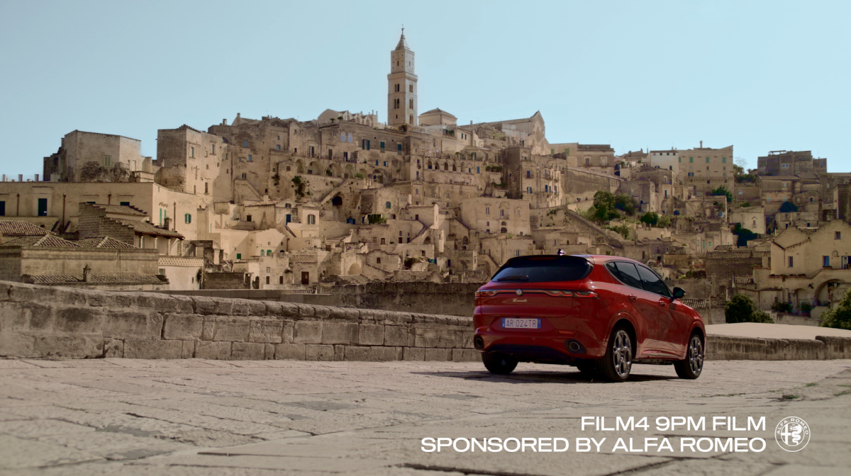 An Alfa Romeo in front of a city as part of an ad