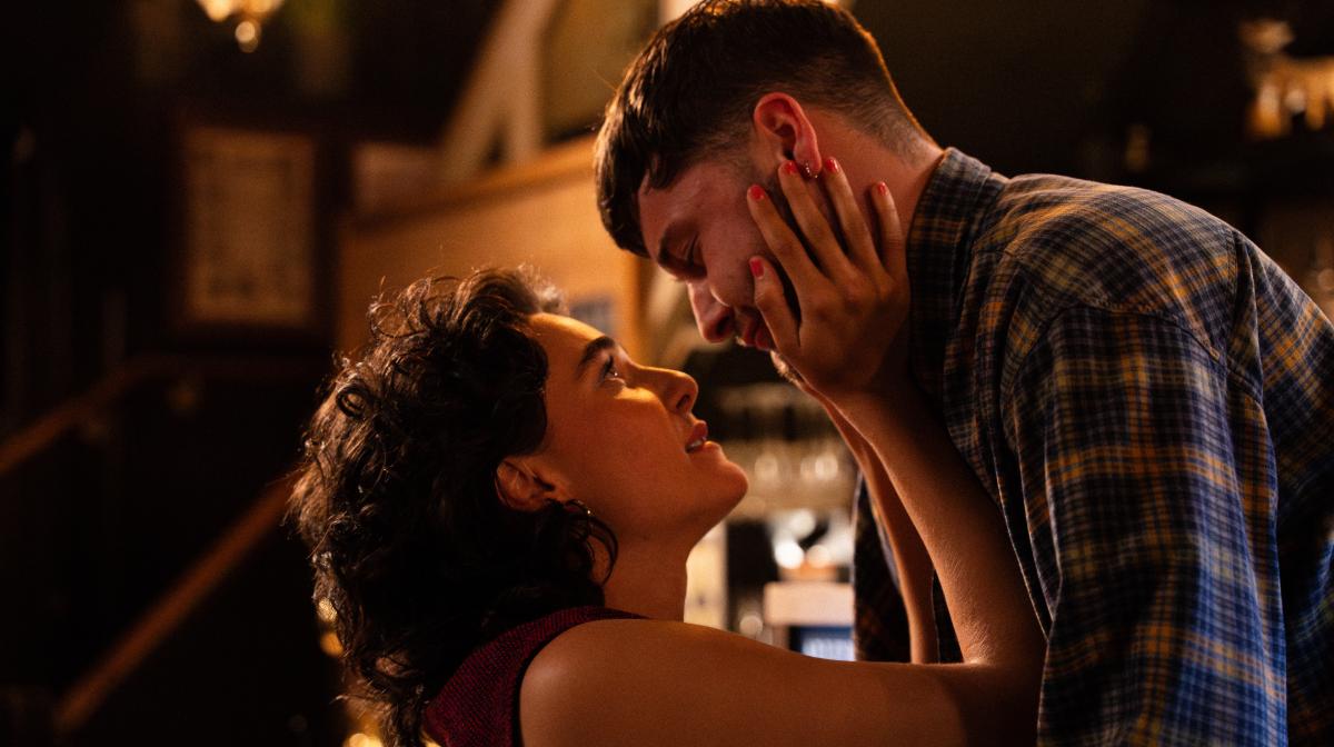 Dark haired woman with hands on face of dark haired man