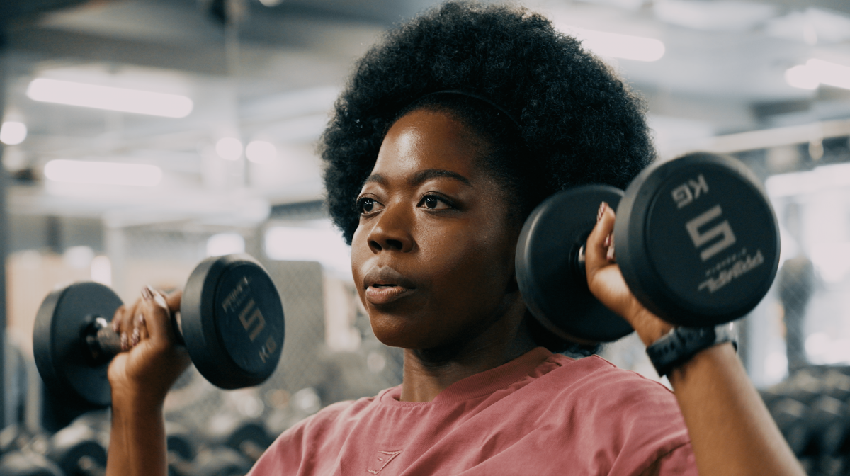 It shows a woman lifting weights in a gym