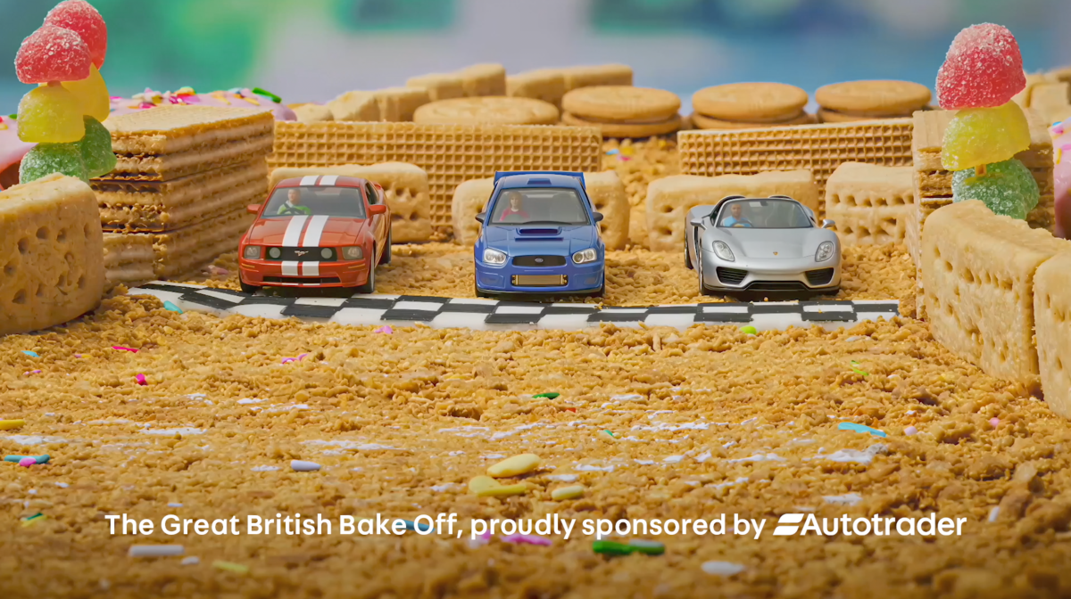 Tiny cars against a back drop of biscuits and sweets, alongside Autotrader's sponsorship tagline. 
