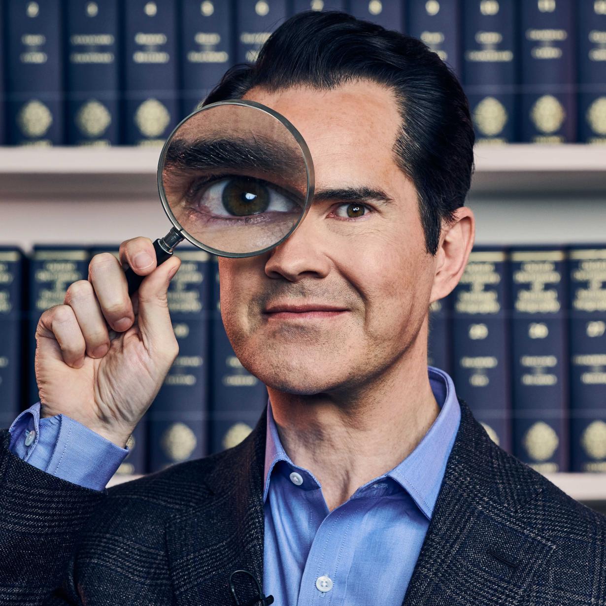 Jimmy Carr looking through a magnifying glass.
