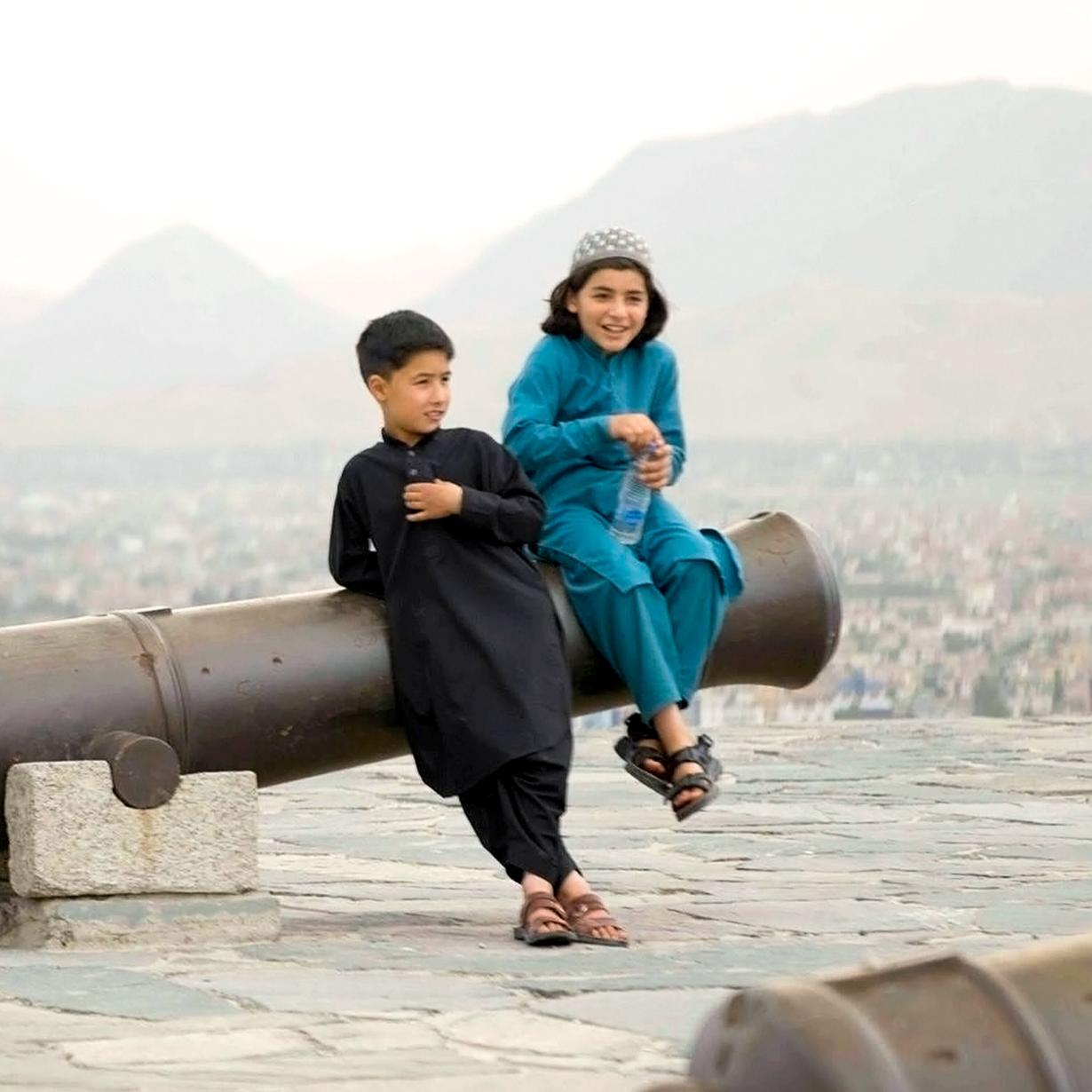 two children sitting on a canon