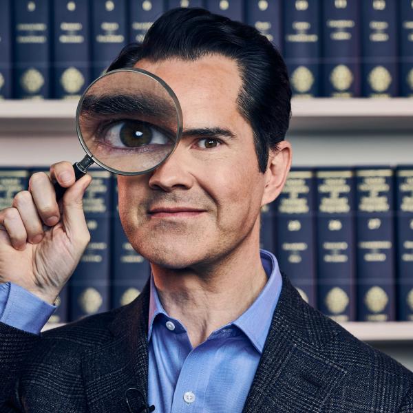 Jimmy Carr looking through a magnifying glass.